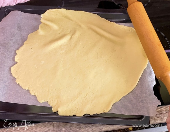 Из теста сформировать шар и раскатать в круглый пласт. Выложить пласт на противень, застеленный бумагой для выпечки.