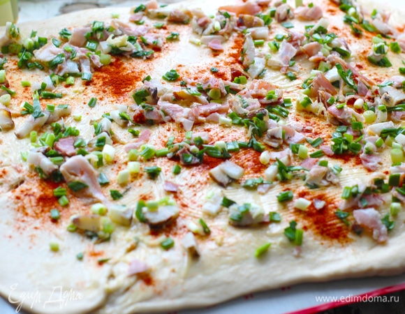 Подошедшее тесто тонко раскатать. Можно смазать растопленным смальцем или любым маслом. Посыпать острой паприкой. Равномерно выложить начинку.