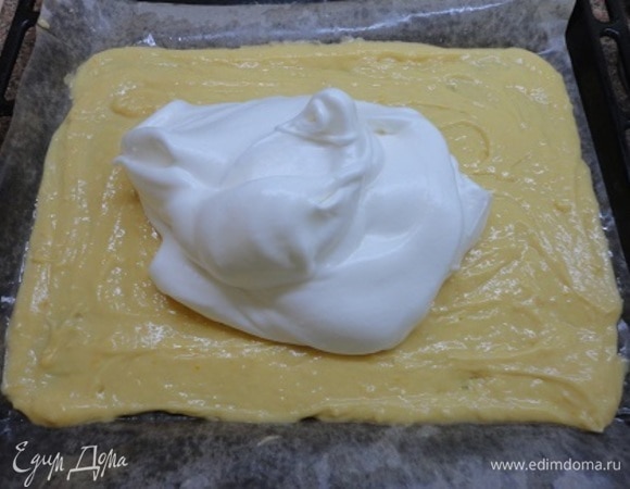 Противень застелить бумагой, смазанной маслом, и выложить тесто прямоугольником примерно 30х23 см. Белки взбить с лимонным соком в пену, затем частями добавлять сахарную пудру и взбить до устойчивых пиков. Выложить белки на тесто.