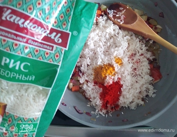 Добавить в сковороду к овощам рис, куркуму и паприку. Поджарить пару минут, чтобы все вкусы соединились.