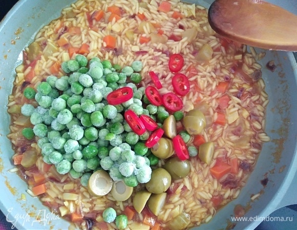 Перец халапеньо нарезать колечками, оливки — пополам. Вместе с горошком добавить к рису. Перец сначала нужно попробовать. У меня был средней остроты, семена я не убирала. Если ваш перец очень острый, то семена лучше убрать. Готовить еще 10 минут, помешивая. Огонь средний.