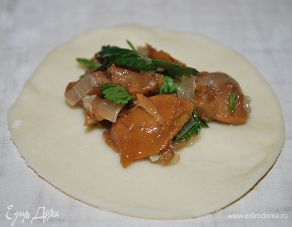 Раскатайте тесто, вырежьте кружки чуть больше, чем на пельмени. На середину теста выложите начинку из грибов.