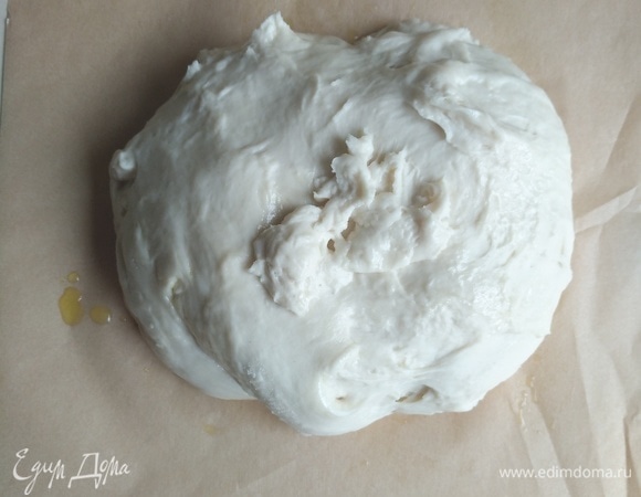 Достаем тесто, делим на 2 части, кладем на пергамент, предварительно капнув на него пару капель оливкового масла.