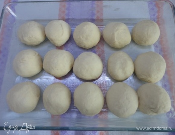 После подъема теста разделить его на 15 шариков весом каждый примерно 60 г. Форму смазать сливочным маслом и дать заготовкам расстояться для увеличения в 2 раза.