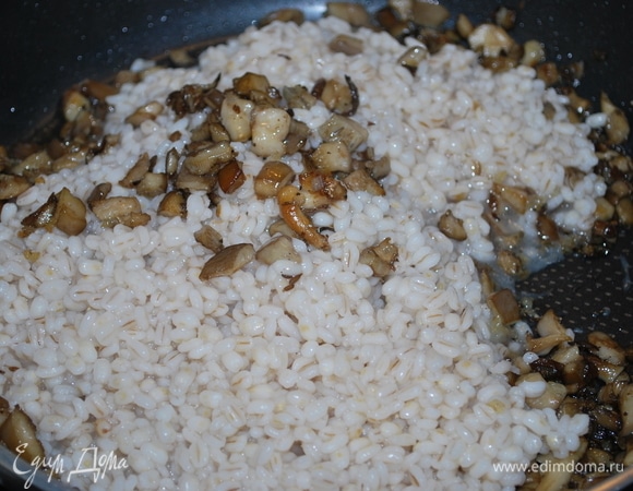 К обжаренным луку и грибам добавьте отваренную крупу, перемешайте все вместе.