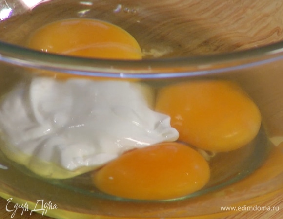 В отдельной миске венчиком смешать яйца и йогурт, затем медленно влить оливковое масло, продолжая вымешивать, пока не получится однородная, гладкая масса.