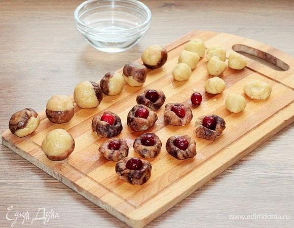 Разделите отдельно шоколадное и белое тесто на 16 частей и скатайте в шарики. Затем немного расплющите каждый шарик в лепешку. Положите на 16 лепешек замороженную клюкву и закройте второй лепешкой. Сформируйте шарик из 2 лепешек и клюквы. У меня крупная клюква (называется «Канадская»).