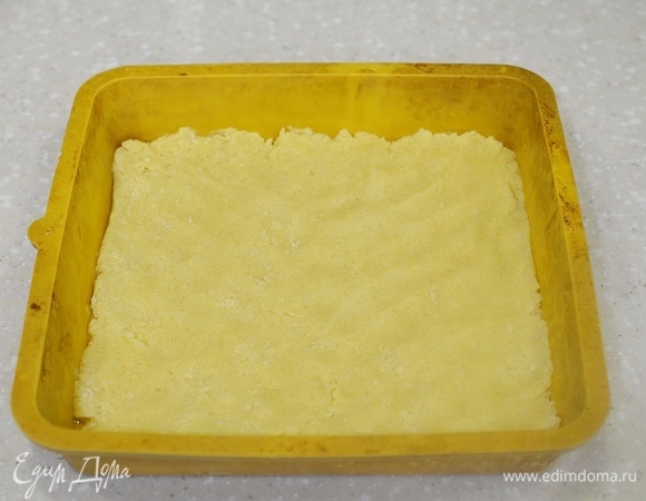 В форму, пригодную для использования в микроволновке, выложите первую половину теста и распределите по дну.