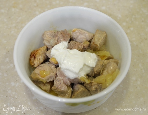 Затем достаньте посуду с мясом, добавьте сметану, перемешайте. Верните в микроволновку. Продолжайте готовить на минимальной мощности еще 10 минут.