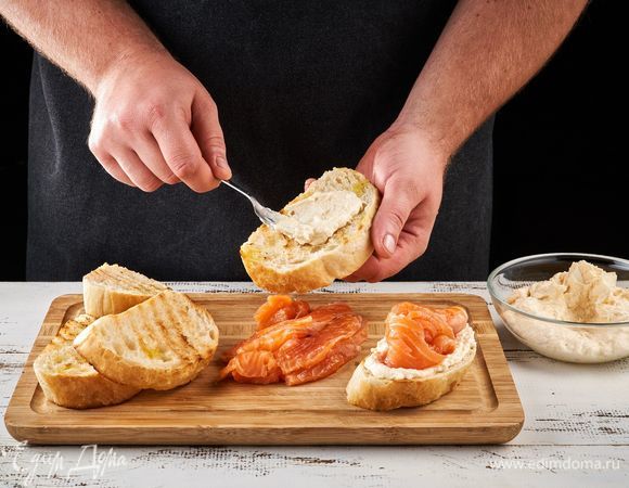 Смажьте креветочным кремом поджаренный хлеб, выложите сверху кусочки форели и украсьте зеленью. 