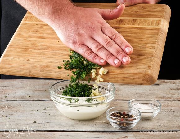 Займитесь соусом. Чеснок и укроп мелко порубите. Добавьте в сметану, посолите, поперчите и перемешайте.