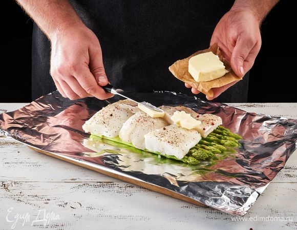 Выложите в фольгу сливочное масло, рыбу, спаржу, мини-кукурузу и черри.