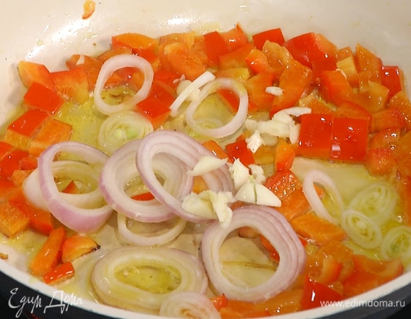 Лук почистить и нарезать тонкими кольцами, чеснок почистить и мелко порубить, добавить все в сковороду к перцу.