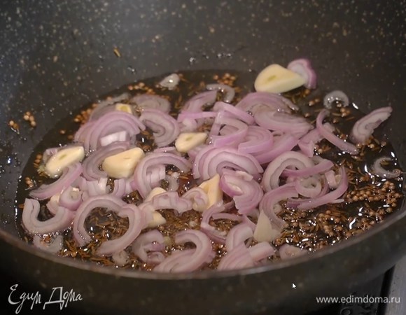 В разогретую сковороду вок всыпать кориандр, зиру и прогреть, затем влить оливковое масло, добавить шалот и чеснок, все перемешать и обжарить.