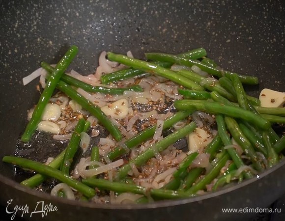 Перец чили нарезать кольцами, выложить к луку с чесноком и перемешать, затем добавить стручки фасоли и обжарить так, чтобы фасоль осталась хрустящей, но не была сырой.