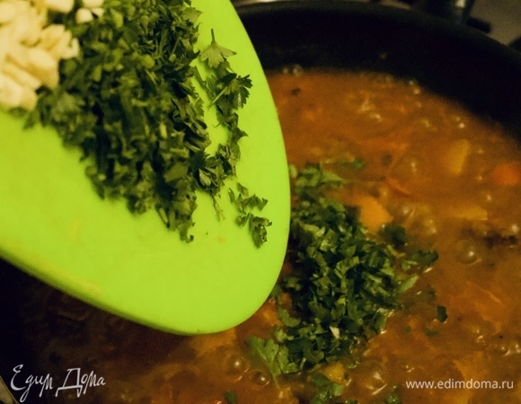 Добавляем мелко нарезанную зелень кинзы и петрушки, затем — чеснок. Перемешиваем.