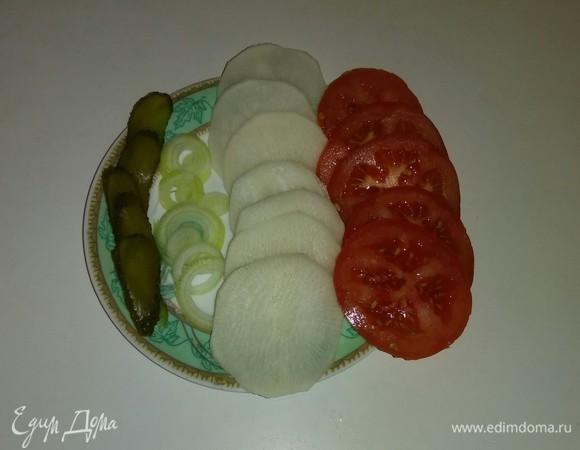 Помидор, дайкон и репчатый лук нарезаем кружочками. Соленый огурец режем дольками.