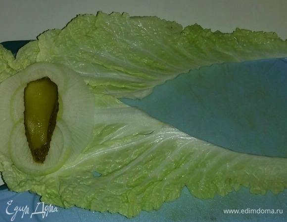 Начинаем собирать салат. На верхнюю часть листа китайского салата кладем кружок дайкона, затем кружочки репчатого лука, дольку соленого огурца.