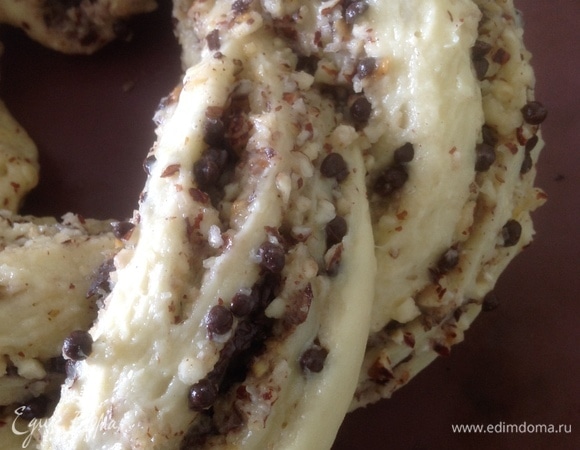 Разрезать рулет вдоль на две части, отступив от начала сантиметров 5, вывернуть начинкой вверх и сплести косу. Соединить рулет в виде кольца и оставить в теплом месте на 10 минут. Выпекать в разогретой до 180°C духовке около 25 минут.