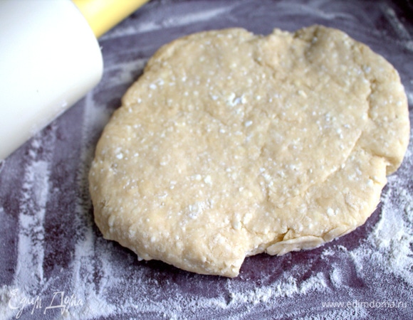 Раскатать липкое тесто на поверхности с мукой.