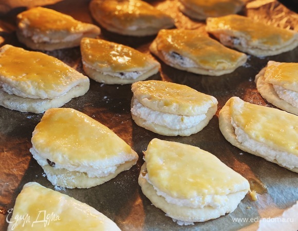 Посыпать рабочую поверхность мукой, отщипывать от теста небольшие шарики и раскатывать скалкой в овал. На одну часть выложить начинку и закрыть второй половинкой теста. Смазать все сочники с помощью кисточки желтком и выпекать 25–30 минут в разогретой до 180°С духовке.