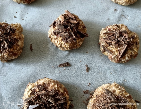 Плоское блюдо накрыть пергаментной бумагой. Сформировать небольшие печенья. Можно сверху положить немного шоколадной крошки для более насыщенного вкуса. Блюдо отправить в морозильную камеру на 5–10 минут (так печенье станет более прочным и сохранит свою форму).