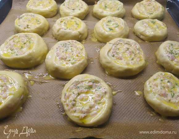 Скатать тесто в рулет (не очень плотный), скрепить края. Ниткой или ножом нарезать на небольшие равные части. У меня получилось 15 частей. Выложить булочки на противень, застеленный пергаментом, чуть примять, смазать взбитым яйцом. Оставить на расстойку на 20–25 минут.