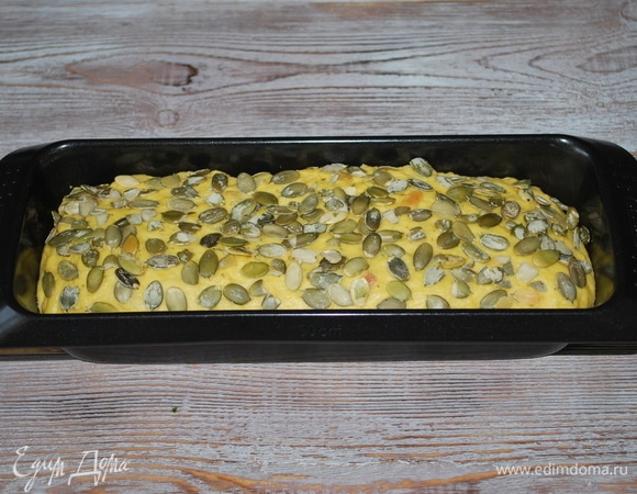 Форму смажьте растительным маслом и выложите туда тесто. Посыпьте сверху тыквенными семечками. Дайте тесту постоять 30 минут.