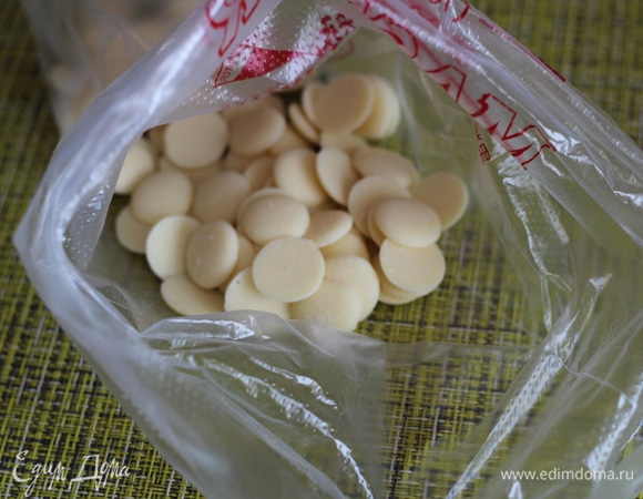 В кондитерский мешок насыпать кусочки белого шоколада, добавить несколько капель красителя.