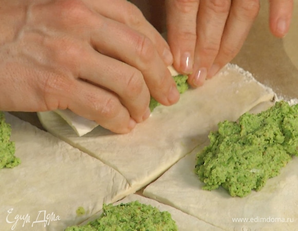 Пласт теста слегка раскатать и разрезать на 4 равных квадрата, на край каждого выложить начинку и свернуть в трубочку, края теста заправить внутрь.