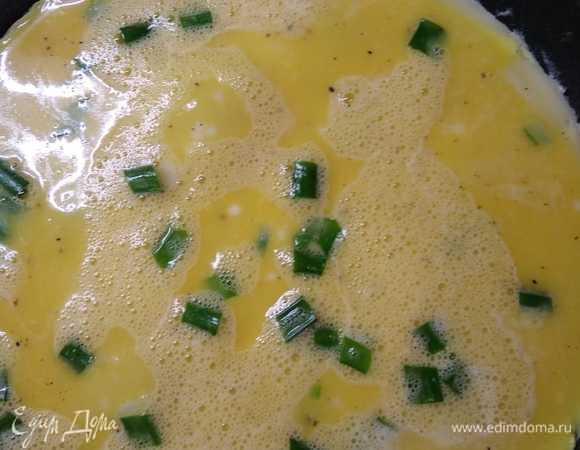 Когда поверхность теста почти застынет, вылейте в сковородку треть яичной смеси и аккуратно распределите ее по поверхности блина.