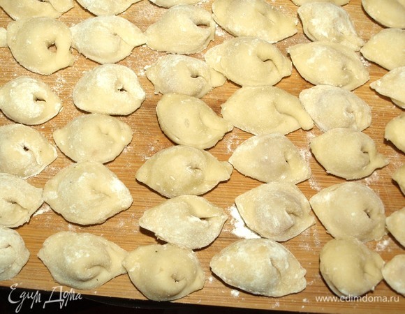 Готовые пельмени выкладываем на доску, припорошенную мукой.