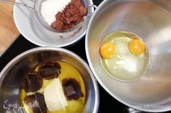 Начнем с шоколадного слоя-основы. Для этого нужно в сотейнике соединить сливочное масло и шоколад. В миске соединить яйца с сахаром и щепоткой соли. Просеять и соединить вместе муку и какао.
