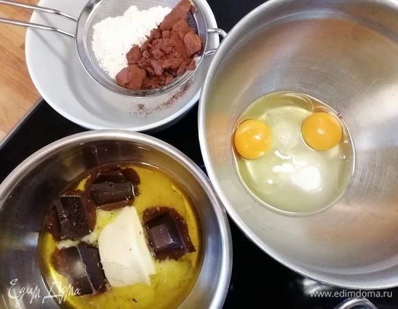 Начнем с шоколадного слоя-основы. Для этого нужно в сотейнике соединить сливочное масло и шоколад. В миске соединить яйца с сахаром и щепоткой соли. Просеять и соединить вместе муку и какао.