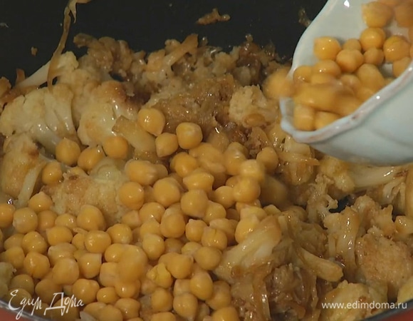 Цветную капусту разобрать на небольшие соцветия, выложить к луку с чесноком, посолить и обжарить до готовности, затем добавить 2 ст. ложки оливкового масла, нут без жидкости и все перемешать. 
