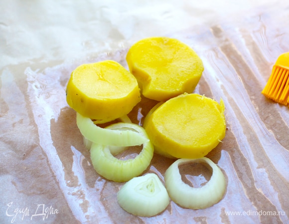 На пергамент выложить нарезанный колечками лук, чуть посолить. На лук — очищенный и нарезанный кружками вареный картофель, тоже немного посолить.