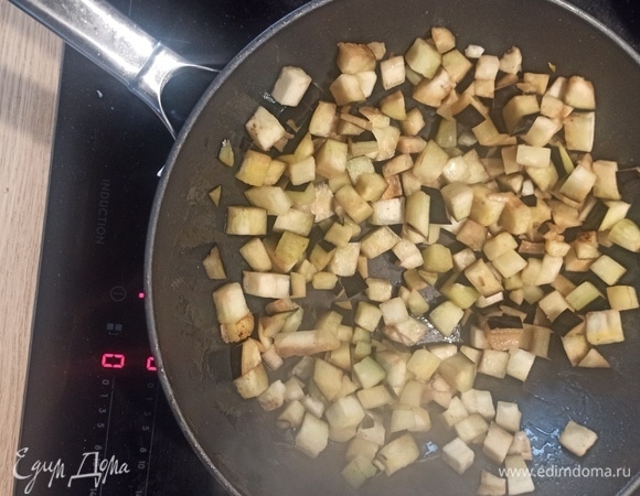 То же самое делаем с баклажаном. Нарезаем кубиками, пассеруем в той же сковороде 5 минут, складываем в кастрюлю к перцу. Сковороду после каждого овоща мыть не нужно.