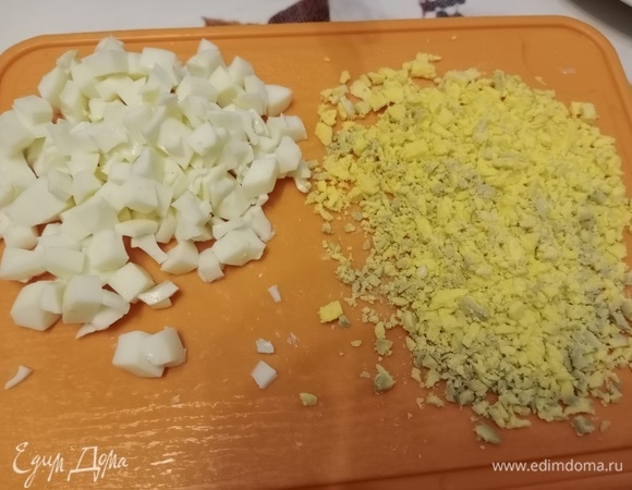 Яйца разделяем на белки и желтки. Белок нарезаем кубиками как получится (все знают, что вареный белок режется как сам захочет). И отправляем белок в миску с нарезанными ингредиентами. Желток измельчаем ножом как можно мельче.