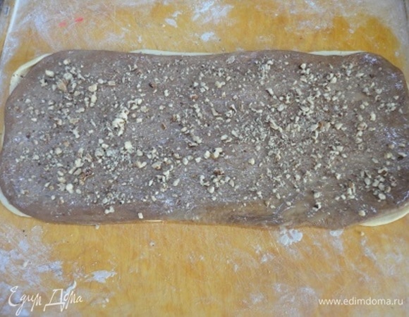 Сначала раскатываем светлое тесто, смазываем его поверхность молоком, сверху укладываем темный слой теста, смазываем его растопленным сливочным маслом, посыпаем измельченными грецкими орехами и по желанию сахаром. Так же поступаем и со второй частью белого и шоколадного теста. Только теперь с изюмом. Сворачиваем в рулет.