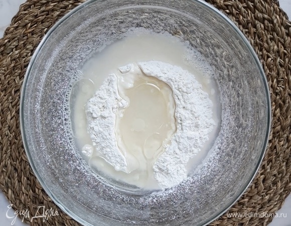 Муку просеиваем в миску и делаем небольшое углубление. Добавляем соль. Наливаем теплую воду и растительное масло.