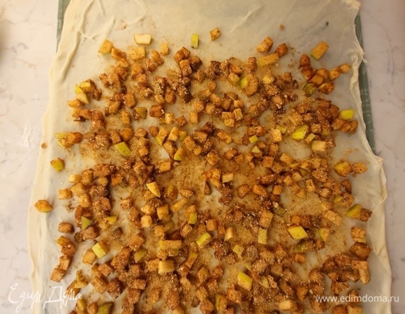 Тесто раскатываем с минимальным добавлением муки и максимально тонко. Можно его аккуратно потянуть руками. Оно должно быть очень тонким и просвечивать. У меня получился прямоугольник размером 40х60 см. Перекладываем его на полотенце. Выкладываем ароматную начинку на тесто и посыпаем молотыми сухарями.