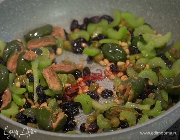 Разогреть в сковороде оливковое масло, выложить сельдерей, кедровые орехи и припустить их, всыпать пеперончино и обжарить, так чтобы орешки стали золотистыми, затем добавить оливки, изюм, каперсы, шафран, цедру и сок лимона, все перемешать.