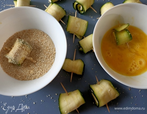 Разбить в тарелку яйцо, немного взбить с помощью вилки. В отдельную тарелку насыпать панировочные сухари. Обмакнуть каждый рулетик сначала в тарелку с яйцом, затем — в сухари.