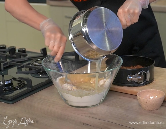 Муку, разрыхлитель, молотый имбирь, мускатный орех и оставшийся сахар всыпать в глубокую миску и перемешать, затем влить масло с сиропом, вымешать однородное тесто и залить им курагу с орехами.