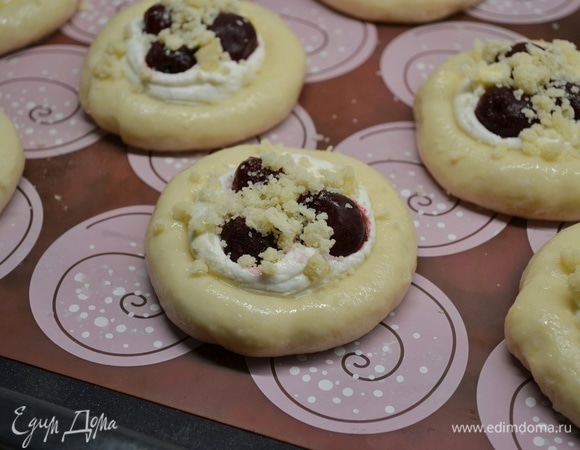 Смазать ватрушки яйцом и начинить вишней. Также по желанию сверху можно посыпать песочной крошкой (30 г муки, 30 г сахара, 25 г холодного сливочного масла перетереть руками в крошку).