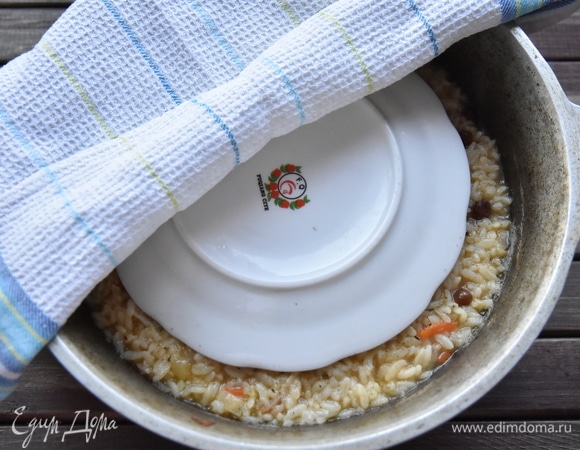 Поверх уложить тарелку и чистое сухое вафельное кухонное полотенце. Накрыть казан крышкой, уменьшить огонь до минимума и оставить на 20 минут. Отключить огонь и дать время отдохнуть плову.