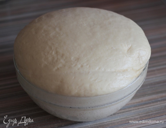 Через час подошедшее тесто выкладываем на рабочий стол, обминаем и промешиваем около 1 минуты.