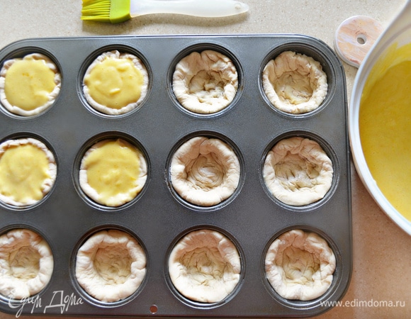 Смажьте формы для маффинов растопленным сливочным маслом. В каждую формочку уложите кружок теста на 2/3 высоты формы. Аккуратно разложите крем по формочкам и выпекайте в разогретой до 200°C духовке примерно 25–30 мин, пока пирожные не станут ярко-золотистого цвета (ориентируйтесь на свою духовку!).