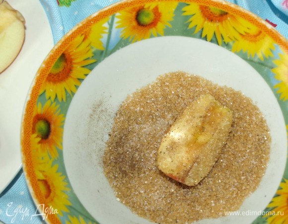 В тарелке смешиваем сахар и корицу. И обваливаем яблочные дольки.