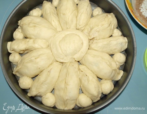 Выкладываем в форму наши заготовки, предварительно застелив низ формы пекарской бумагой, смазанной растительным маслом. У меня форма диаметром 26 см. В центре делаем круглую заготовку и выкладываем швом вниз. Заполняем пространство между фрагментами пирога шариками из теста.